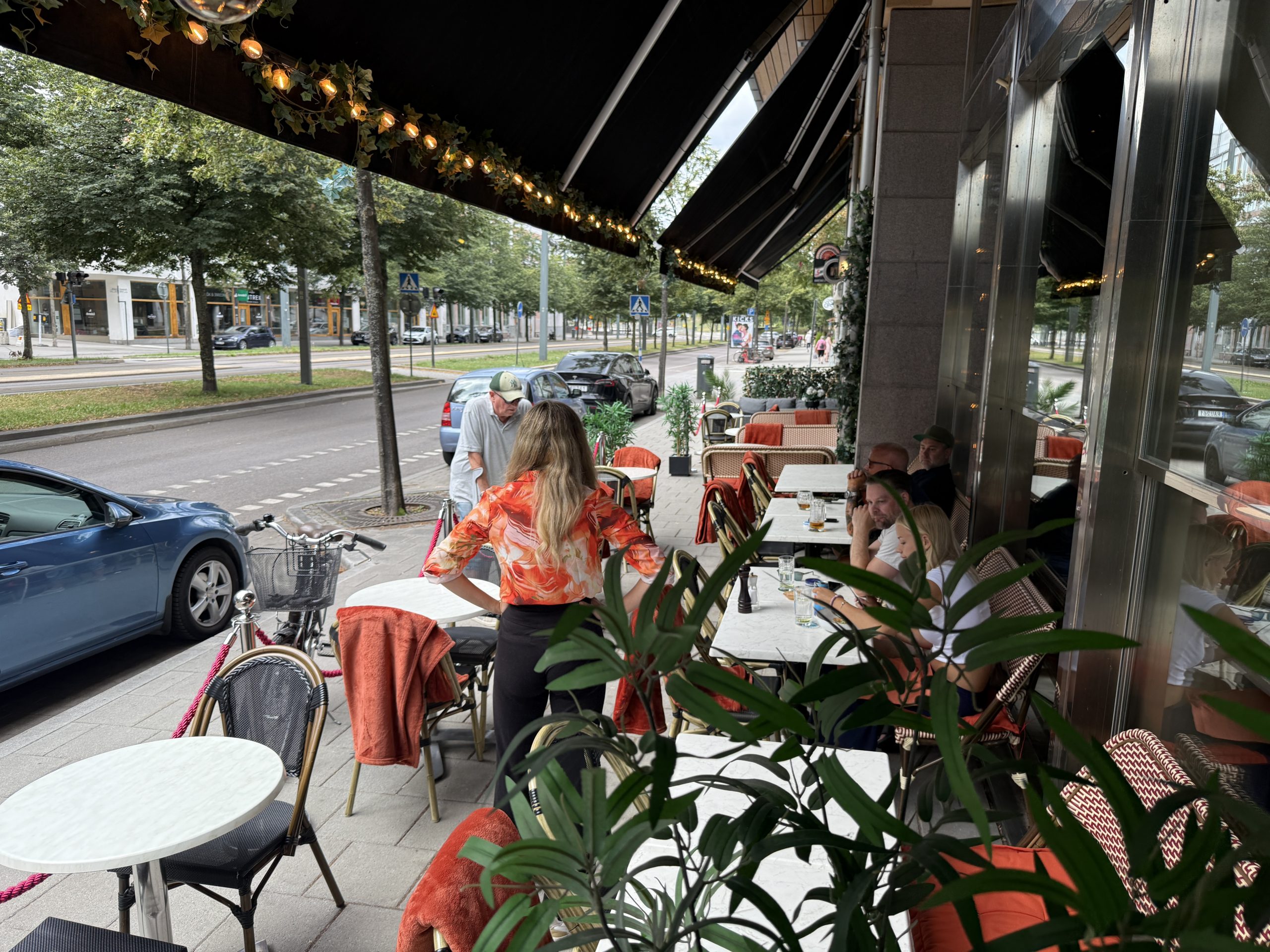 Uteservering med cafébord, stolar och markis